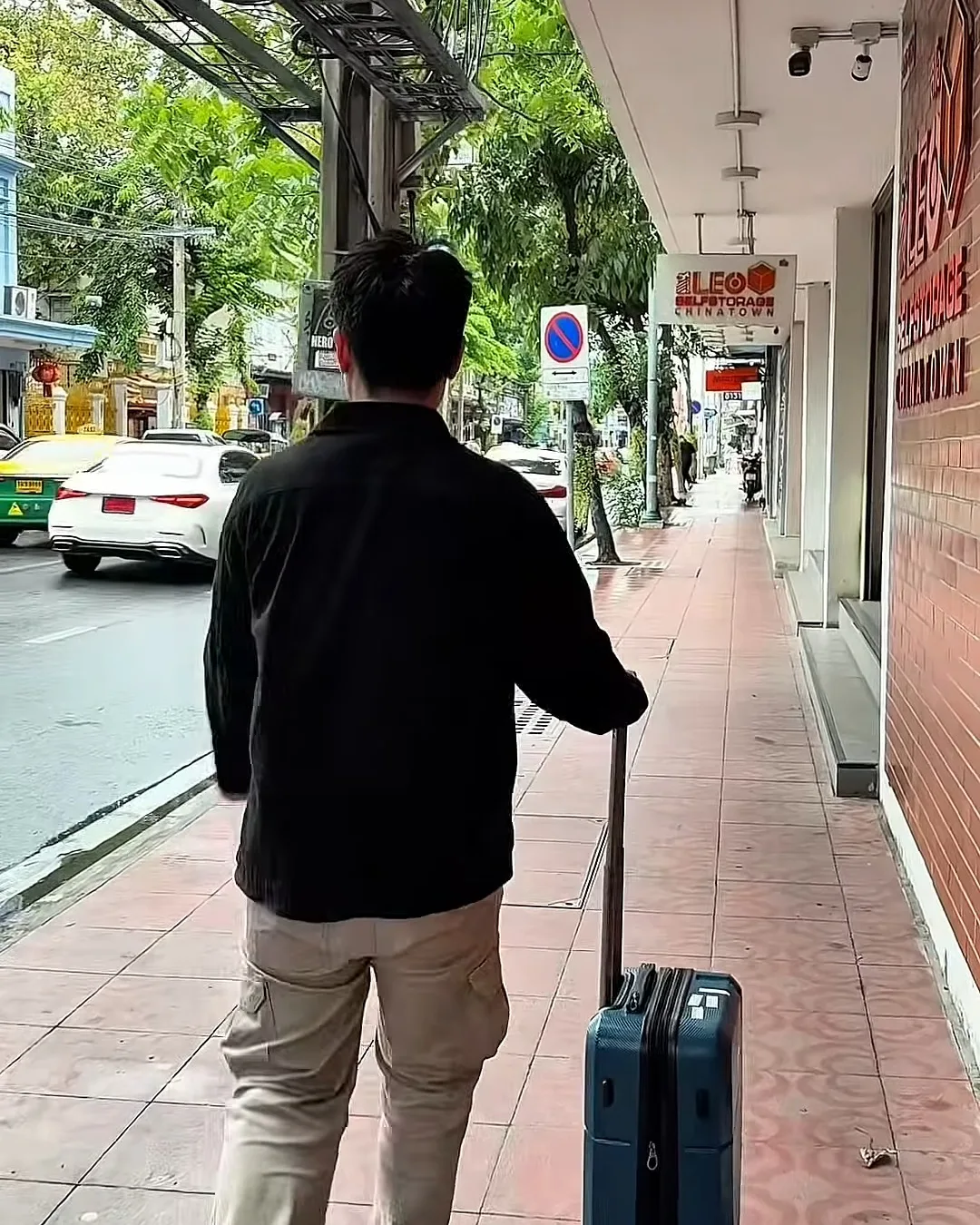 คนลากกระเป๋าเดินทางบนทางเท้าถนนเจริญกรุง มุ่งหน้าไปจุดฝากกระเป๋า LEO Self Storage Chinatown