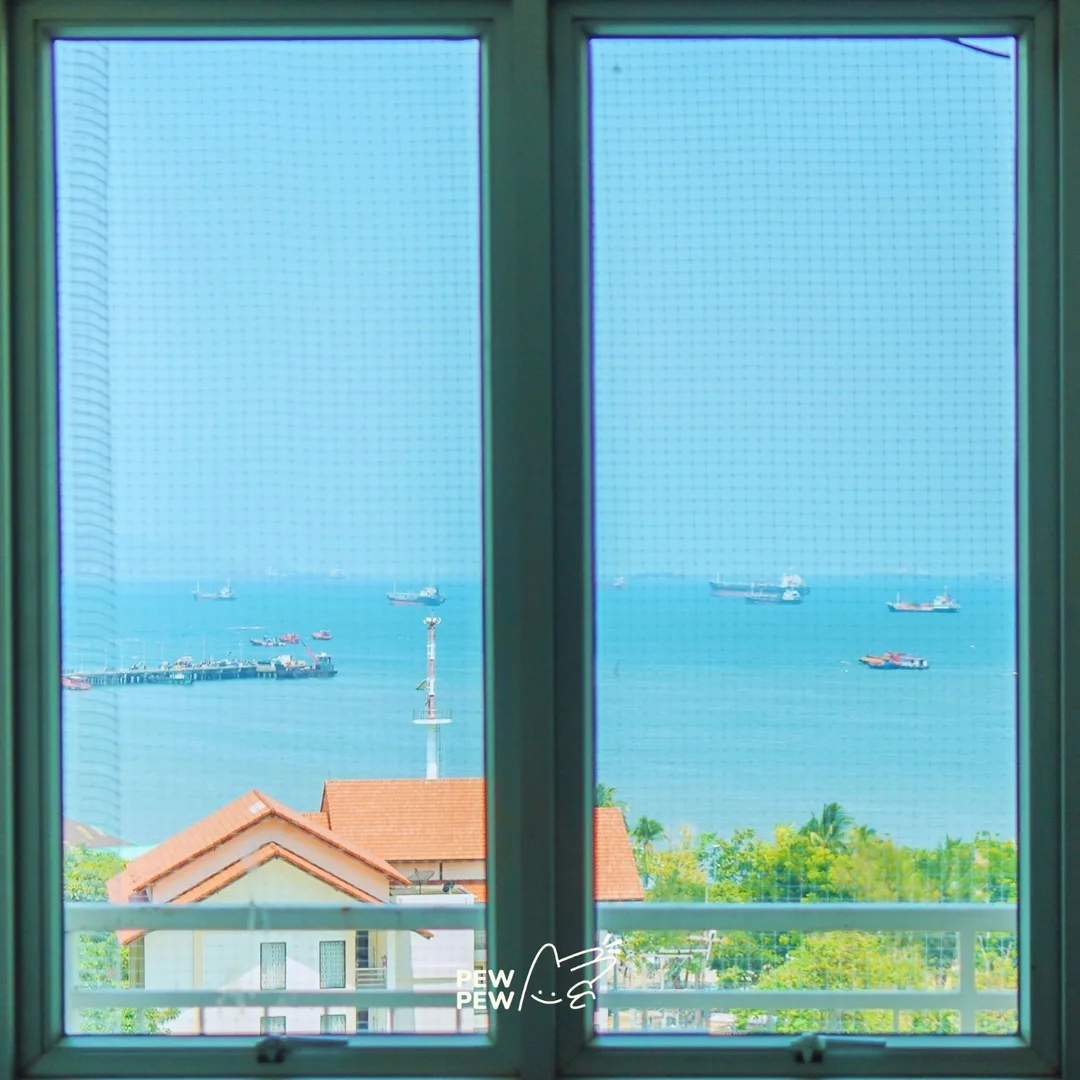 หน้าต่างห้องพัก Cape Racha ศรีราชา มองเห็นทะเลสีฟ้าและท่าเรือ