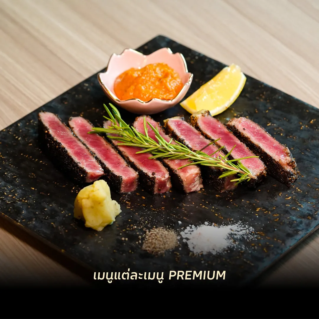 สเต็กเนื้อหั่นชิ้นเคลือบพริกไทยดำ โรสแมรี่ และเลมอน บนจานหินสีดำ