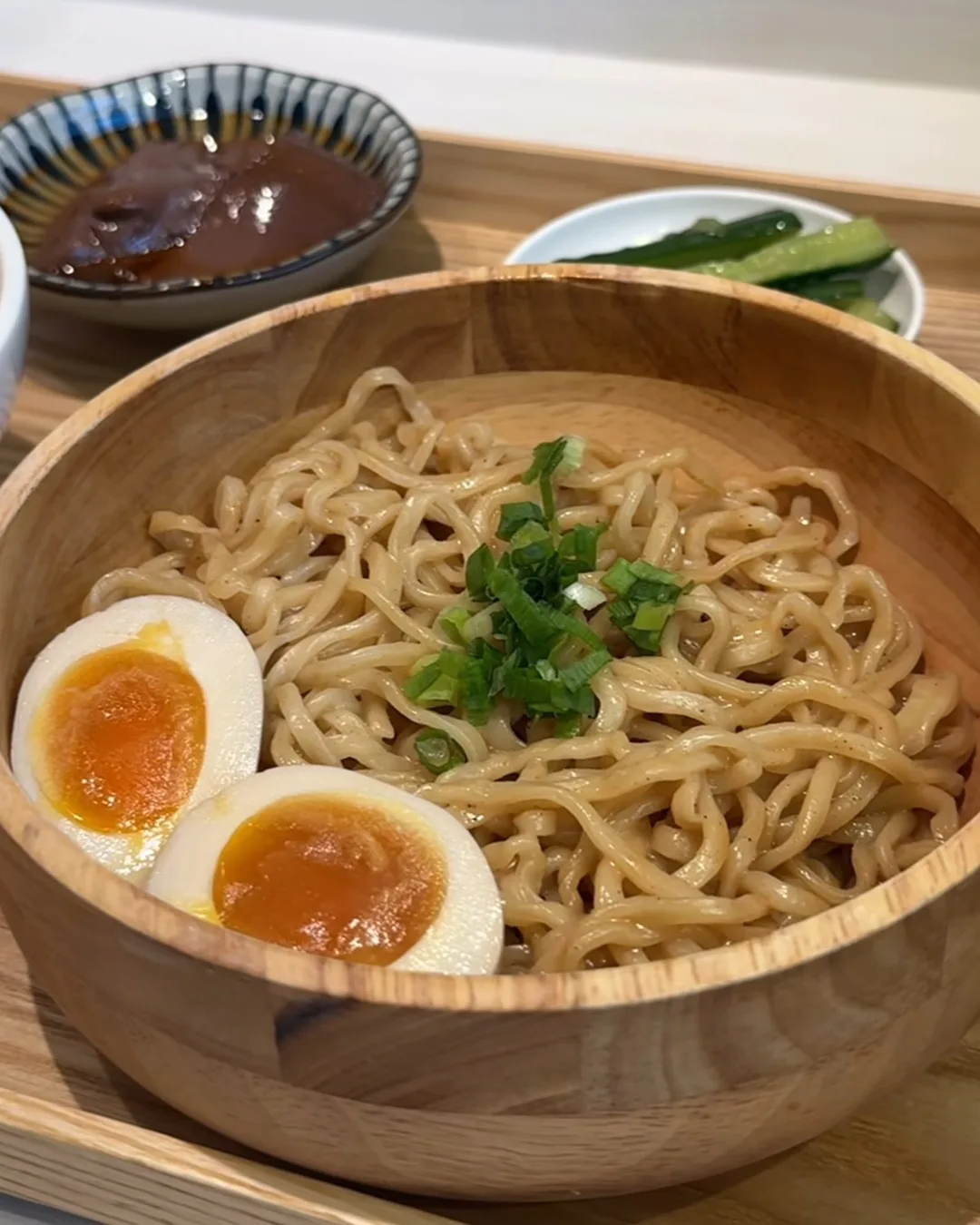 บะหมี่แห้งชามไม้ ไข่ยางมะตูมผ่าครึ่งไข่แดงเยิ้ม โรยต้นหอม กับถ้วยซอสและผักดอง