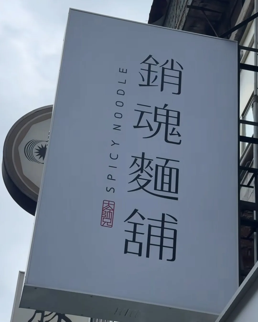 ป้ายร้าน 銷魂麵舖 Spicy Noodle สีเทาแขวนหน้าอาคาร ไทเป