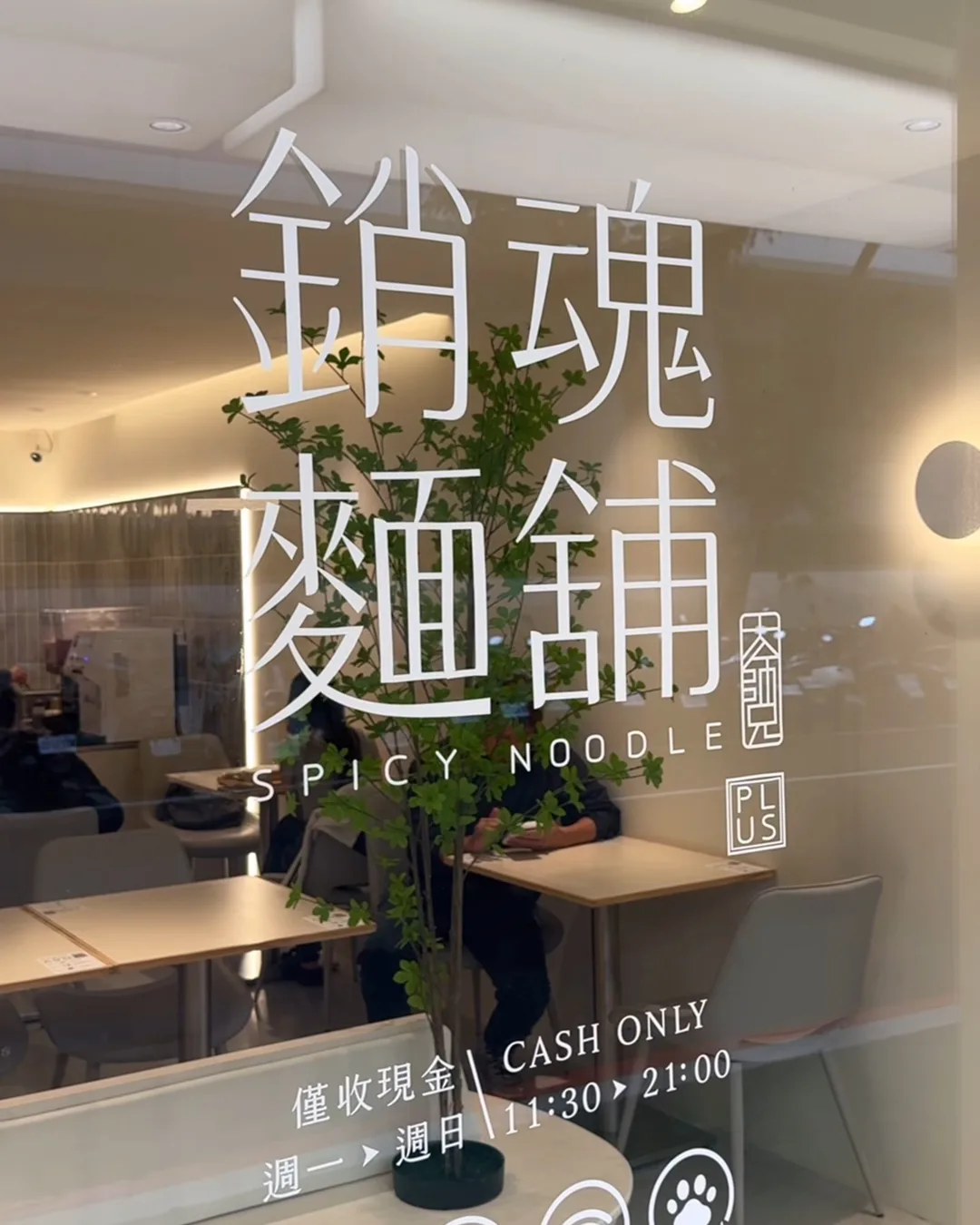 กระจกหน้าร้าน 銷魂麵舖 Spicy Noodle มีป้ายรับเงินสดเท่านั้น เปิด 11:30 ถึง 21:00 และสัญลักษณ์ Wi-Fi สัตว์เลี้ยงเข้าได้