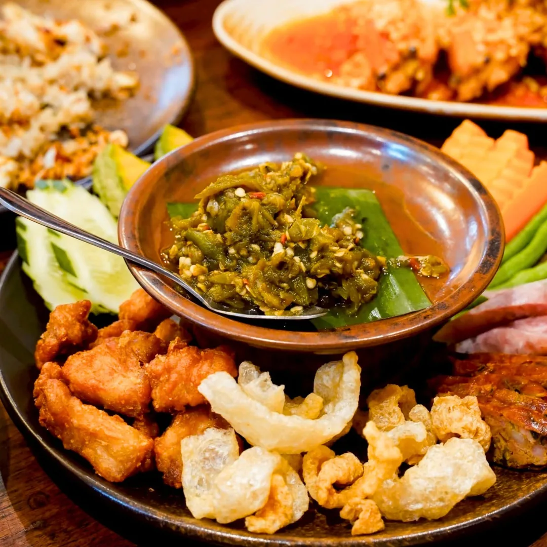น้ำพริกหนุ่มในถ้วยดินเผา ล้อมด้วยแคบหมู ไส้อั่ว หมูทอด และผักลวก ออเดิร์ฟเหนือ ร้านปูนแดงแกงร้อน