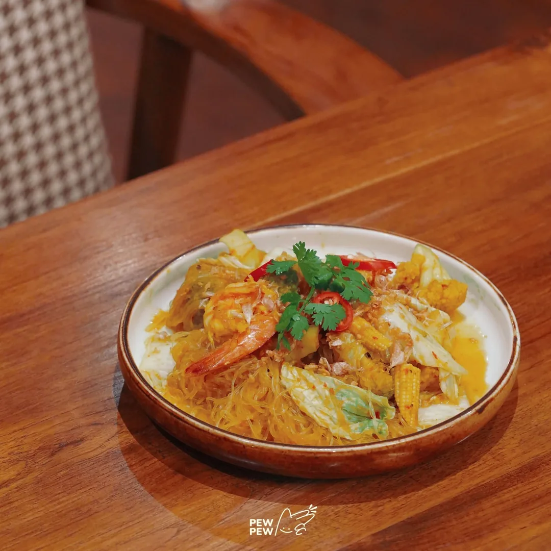 วุ้นเส้นผัดแกงส้มใส่กุ้งและผัก โรยผักชี ในจานกระเบื้อง ร้านปูนแดงแกงร้อน