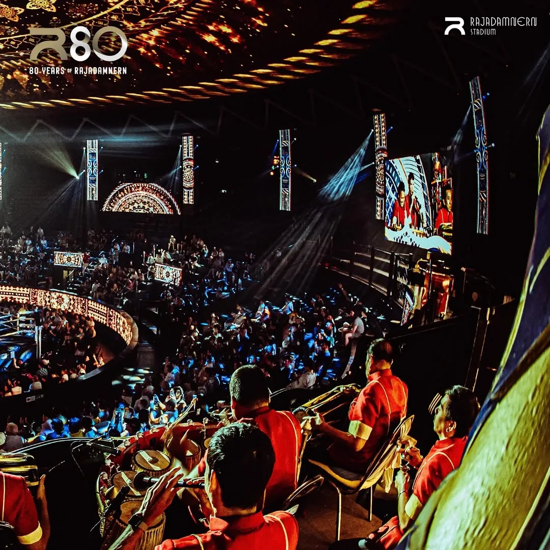 ผู้ชมนั่งเต็มอัฒจันทร์รอบเวทีมวยราชดำเนิน จอภาพขนาดใหญ่ฉายภาพการชก