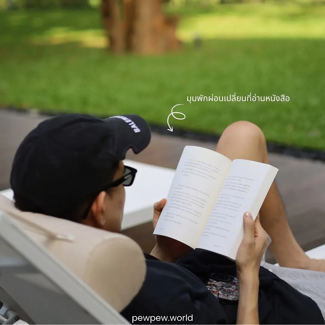 ทีม PewPew นอนอ่านหนังสือบนเตียงอาบแดด ใส่หมวกแก๊ปและแว่นกันแดด ริมสนามหญ้าที่ Riva Vista
