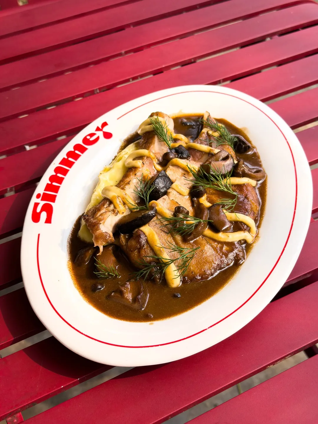 พอร์คชอปย่างเตาถ่านราดเกรวีครีมเห็ด ไอโอลี และผักชีลาว บนจานรีโลโก้ Simmer ร้าน Simmer ตลิ่งชัน