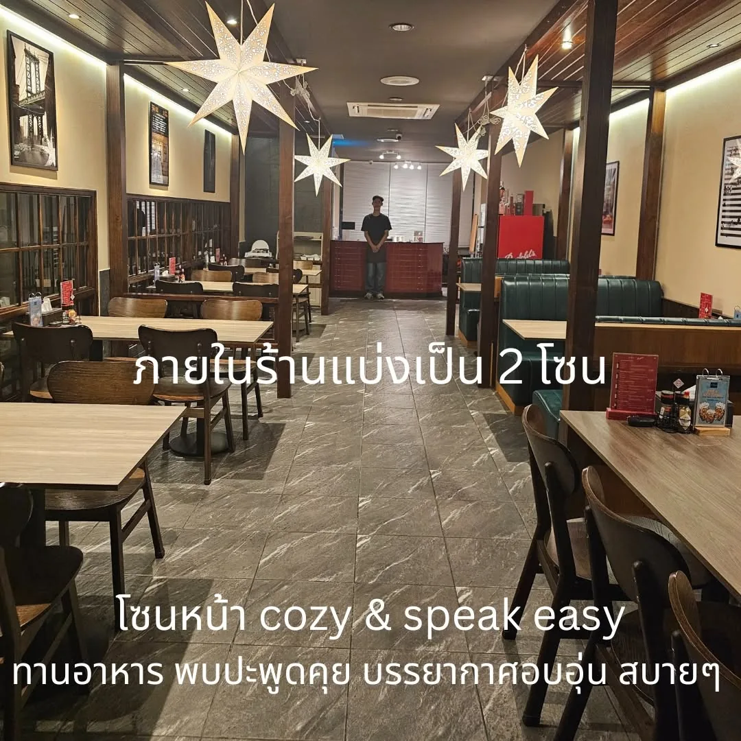 ภายในร้านโซนหน้า โต๊ะไม้และไฟสลัว ข้อความ ภายในร้านแบ่งเป็น 2 โซน