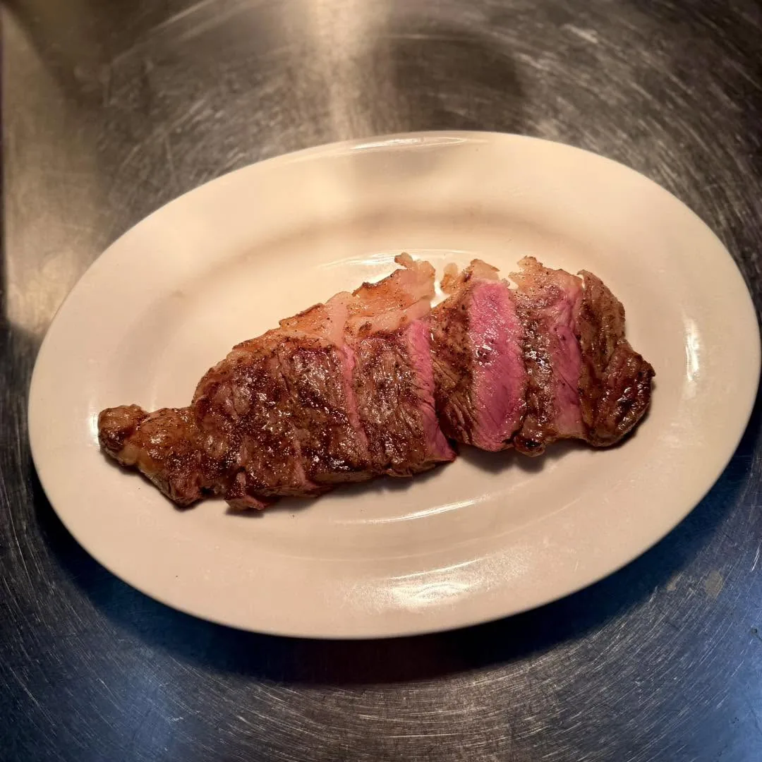 สเต็กเนื้อย่างหั่นชิ้นบนจานขาว ข้างในสีชมพูระดับมีเดียมแรร์