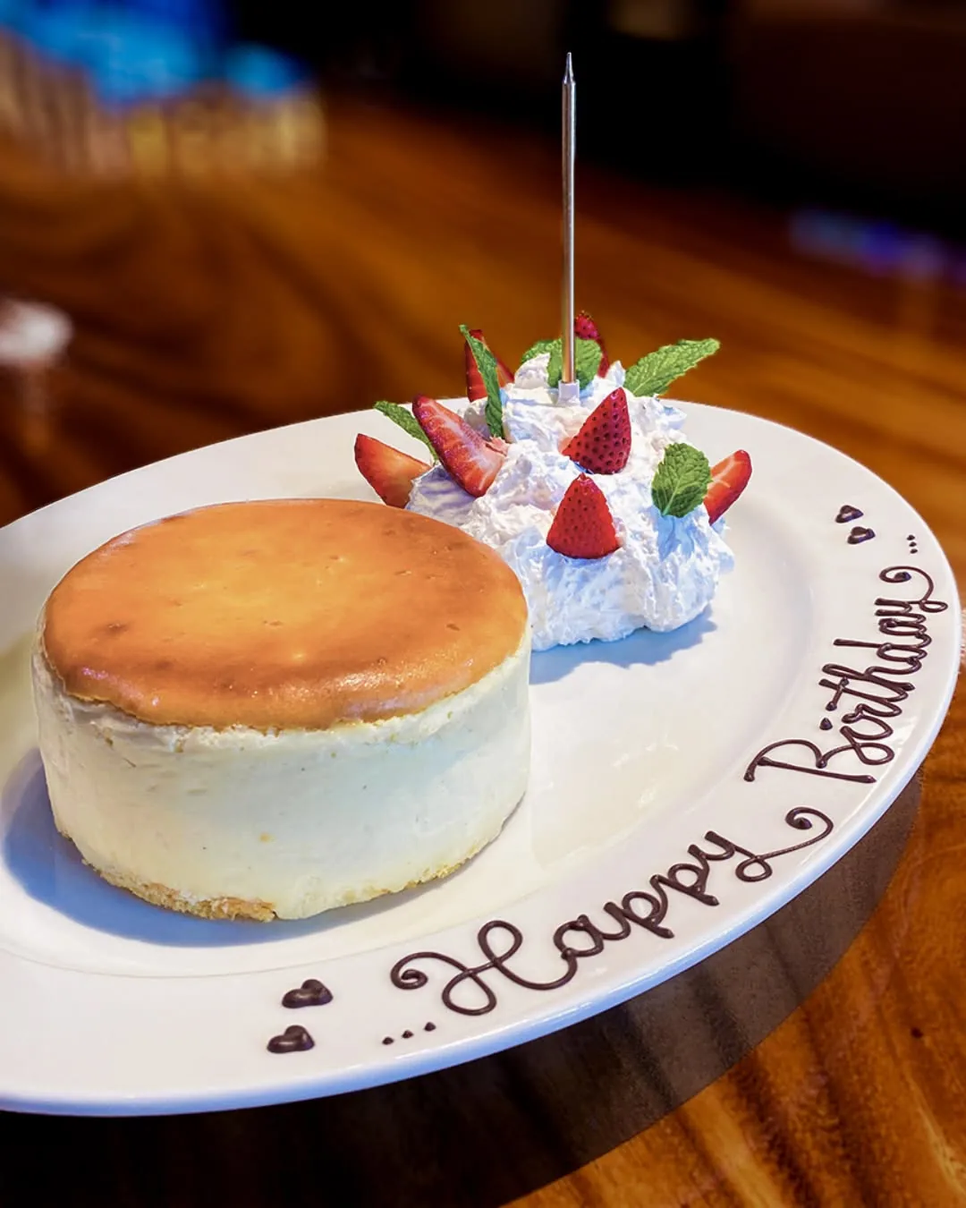 ชีสเค้กบนจานเขียนข้อความ Happy Birthday ด้วยช็อกโกแลต