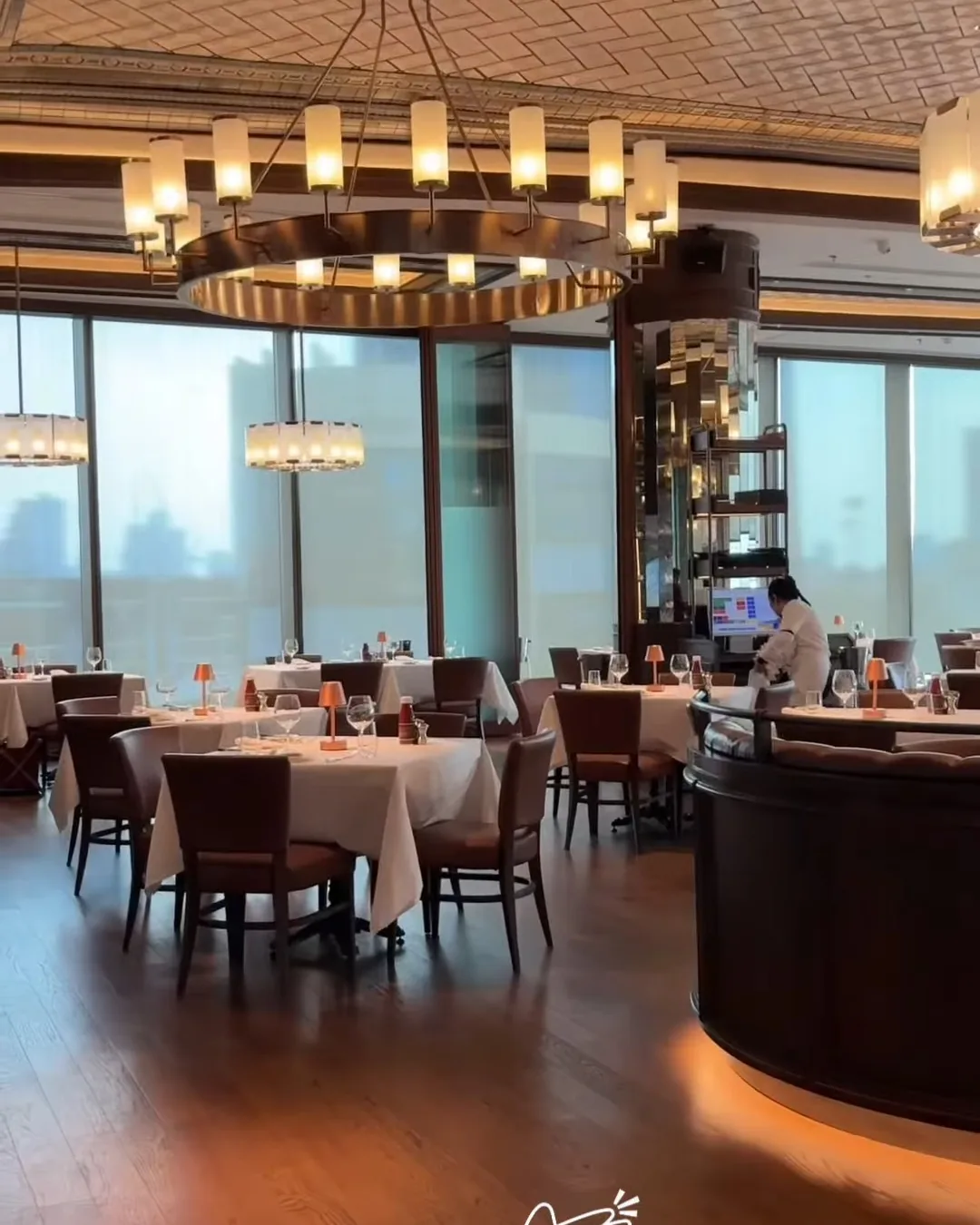 ห้องอาหาร Wolfgang's Steakhouse โคมระย้าทรงกลม พื้นไม้ และโต๊ะผ้าปูขาว
