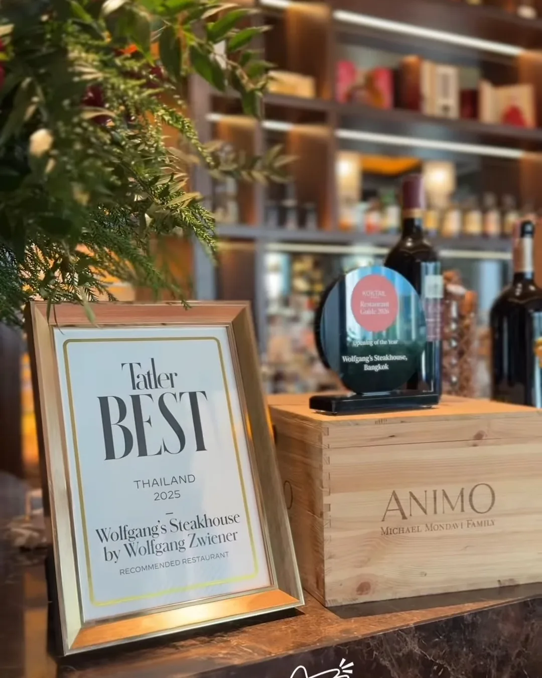 ป้ายรางวัล Tatler Best วางบนเคาน์เตอร์ไม้ในร้าน Wolfgang's Steakhouse