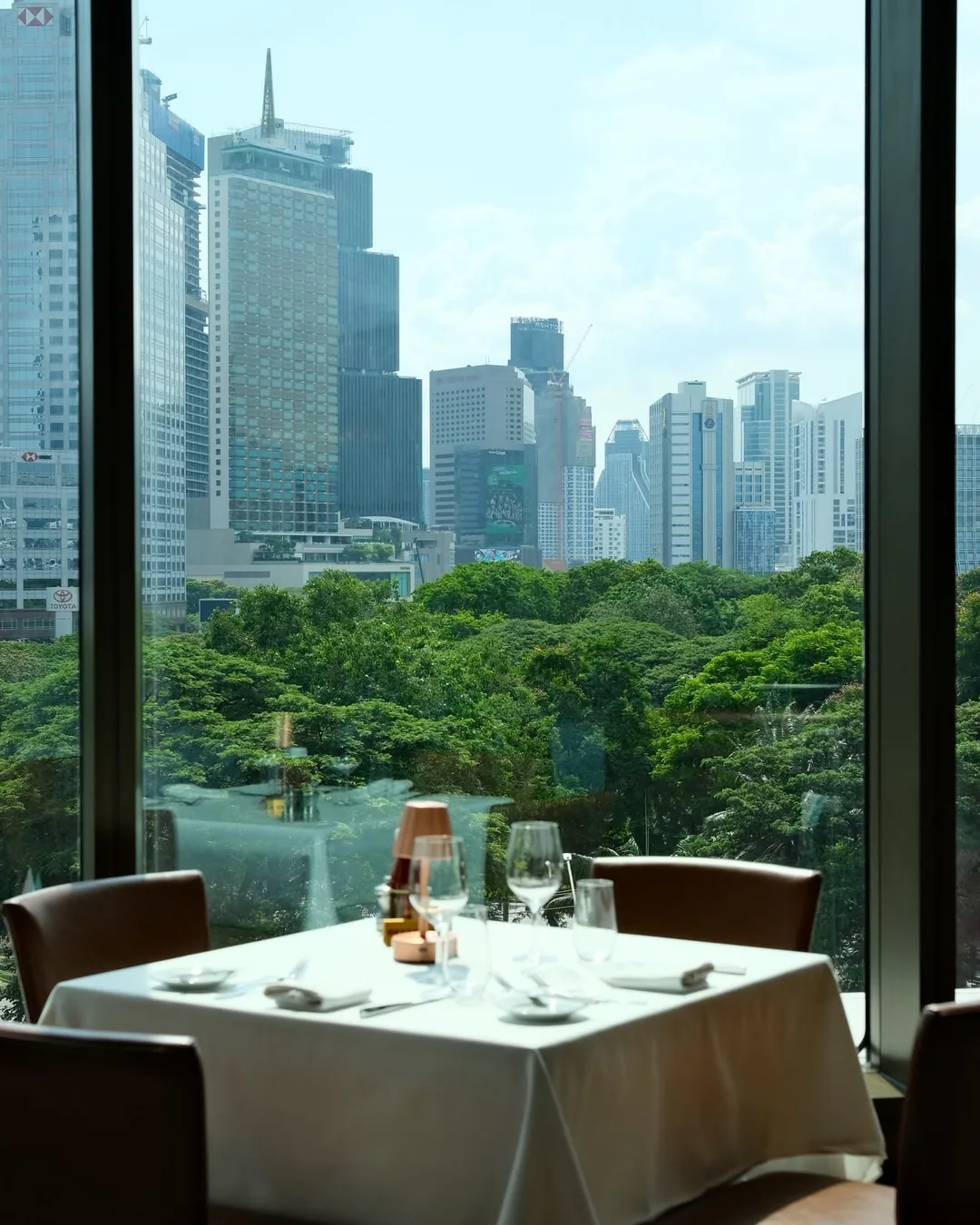 โต๊ะริมหน้าต่างร้าน Wolfgang's Steakhouse มองเห็นสวนลุมพินีและตึกสูงกรุงเทพฯ